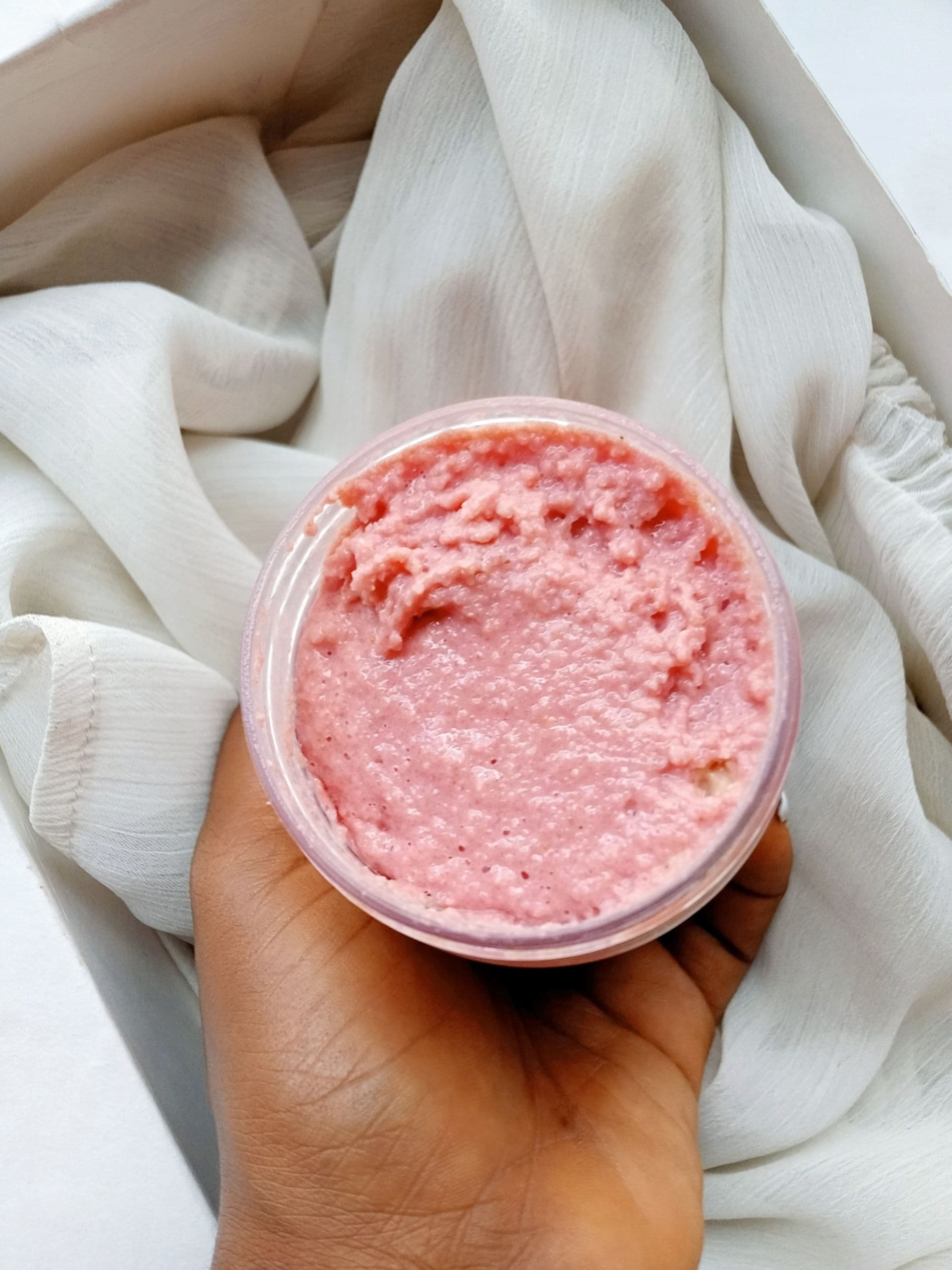 A jar of Salt & Bloom rose body scrub held in the hand